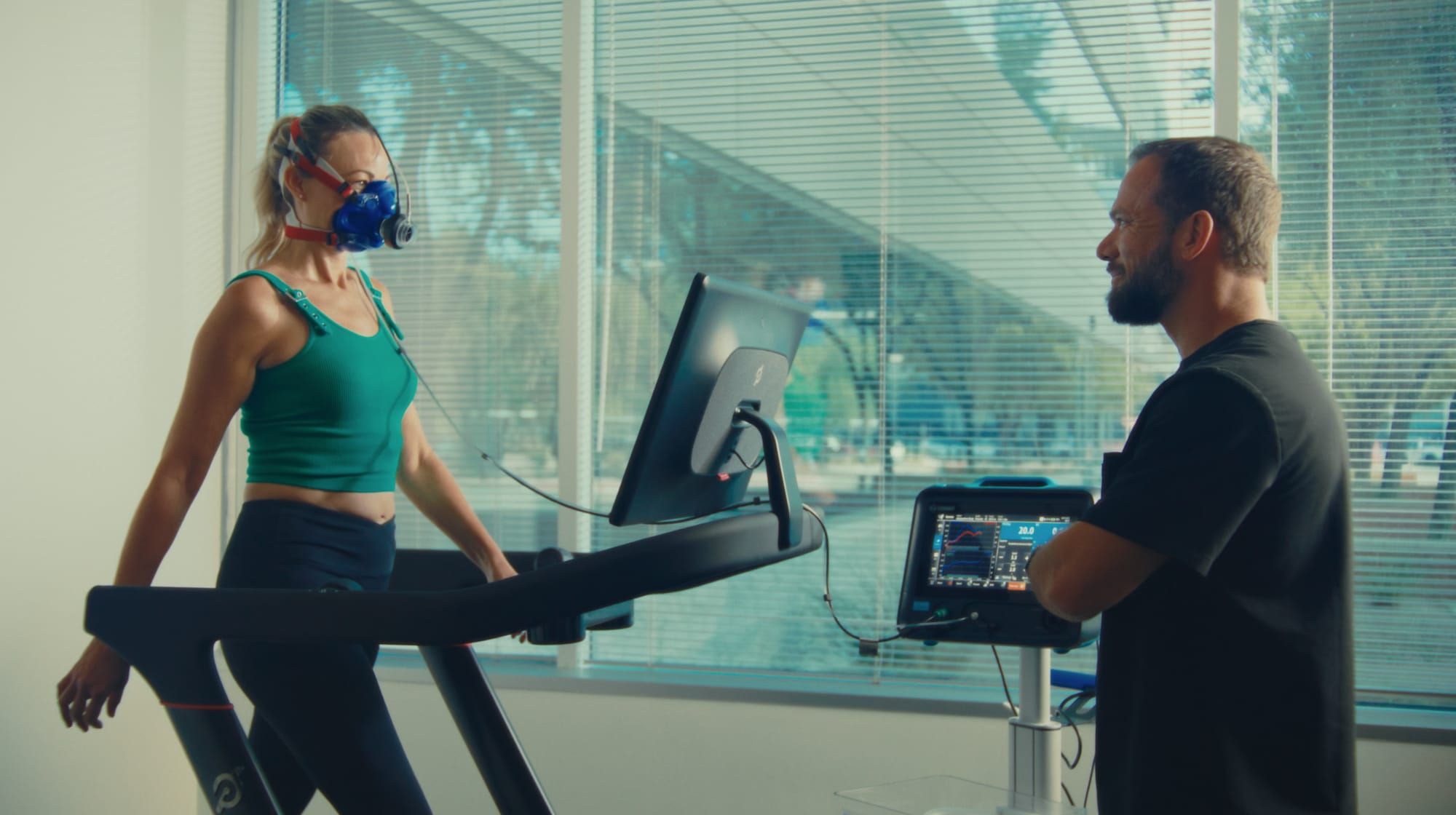 Woman in a VO2 max mask walking on a treadmill while a Preamble Health clinician monitors her metabolic test